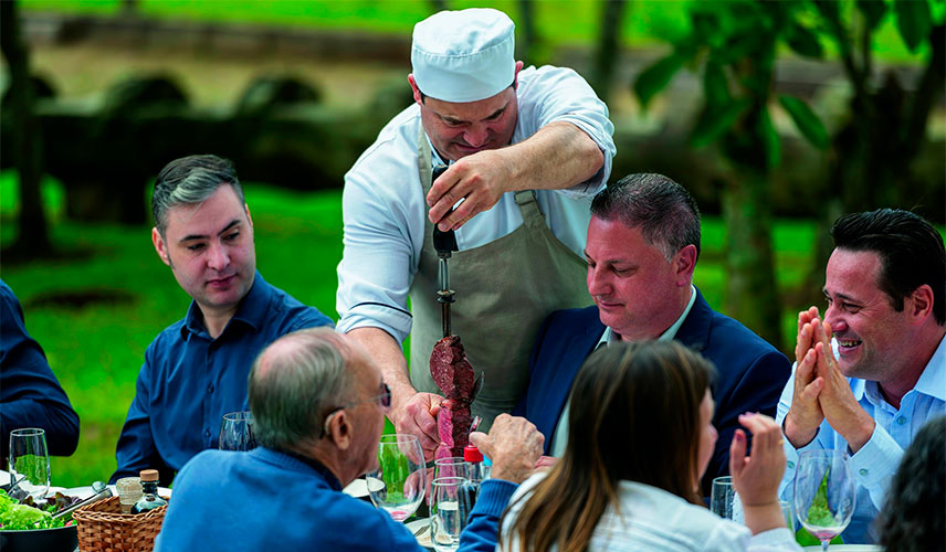 garçom servindo a mesa com espeto de carne
